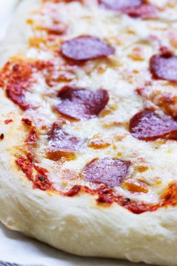 Domates soslu, otlu, ahşap zemin üzerinde sosisli ve peynirli ev yapımı pizza. Kırsal biçim, seçici odak.