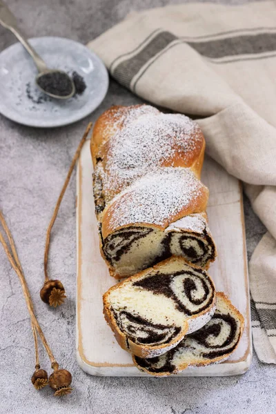 Kuchen mit Mohnfüllung und Saatköpfen auf grauem Betongrund. Rustikaler Stil. lizenzfreie Stockbilder