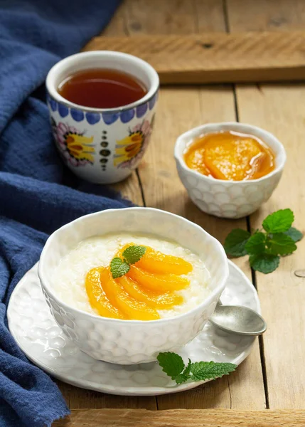Frühstück aus Reisbrei mit Pfirsichmarmelade und Tee. Rustikaler Stil. — Stockfoto