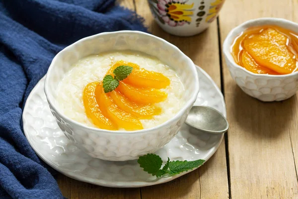 Colazione di porridge di riso con marmellata di pesche e tè. Stile rustico. Fotografia Stock