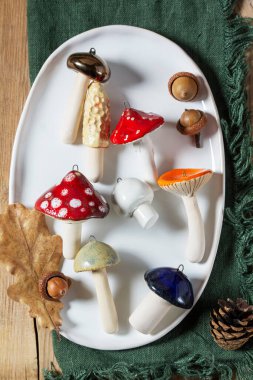 Seramik mantarlar, kozalaklar ve seramik tabakta meşe palamudu ve ahşap masa üstü. Sonbahar konsepti, ev dekorasyonu ya da Noel ağacı. Kırsal biçim.