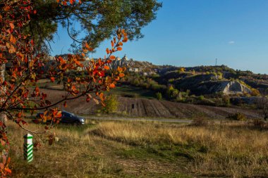 Kuzey Moldova 'da ormanlık ve dağlık arazi boyunca uzanan bir sonbahar manzarası. Kireçtaşı ocaklarında çalılıklar var. Güneşli manzara.