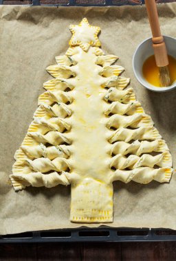 Doldurulmuş ve yumurta yıkamayla fırçalanmış puf böreğinden yapılmış Noel ağacı şeklinde bir turta. Seçici odak.