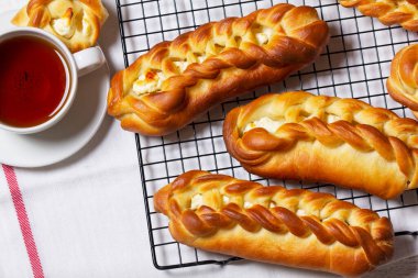 Süzme peynirli çörekler, çay ile servis edilir. Maya esaslı hamur işleri, bir fincan siyah çay ve ahşap bir masada pamuk çiçekleri. Kırsal biçim.