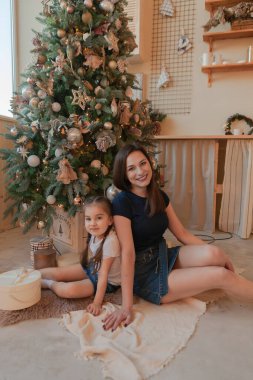 Anne ve kızı Noel ağacında, hediyeleri mutlu bir şekilde sıralıyorlar. Mutlu ve güzel hediyelerle Noel Baba 'yı bekliyor..