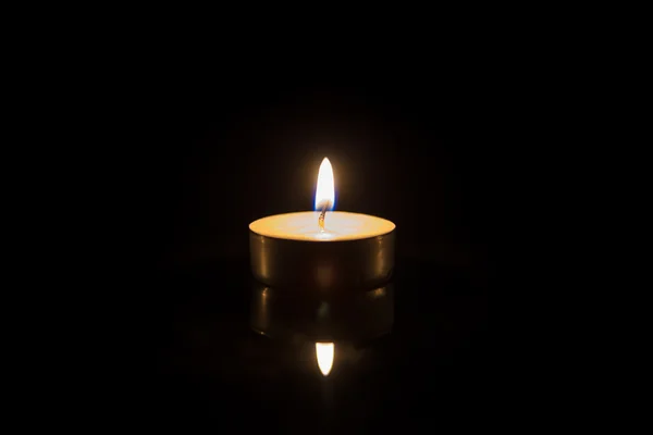 One tea candle with reflection on black — Stock Photo, Image