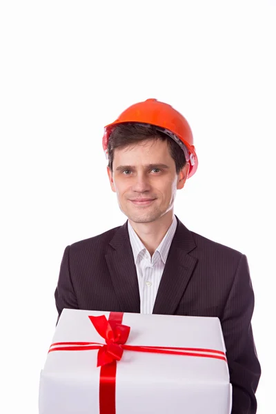 Homem em um terno de capacete dá caixa branca de presente com vermelho — Fotografia de Stock