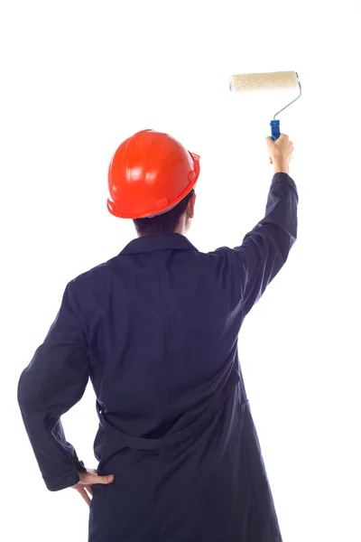 Man in een helm en blauw gewaad verf roller muur, draaien zijn ba — Stockfoto