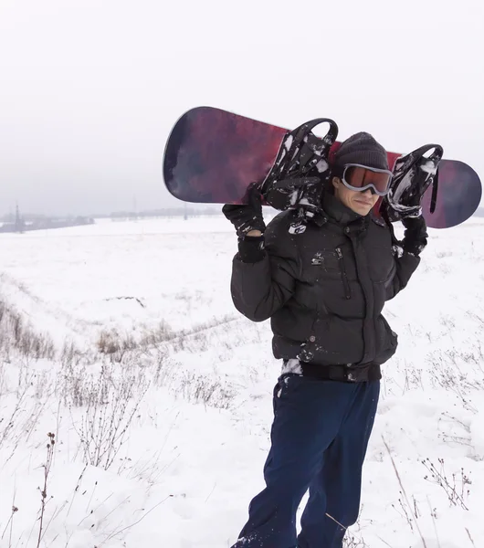 Mann in dunkler Kleidung mit Snowboard-Skibrille auf schneebedeckter Piste — Stockfoto