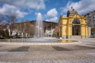 Ana sütunlarda güneşli bir bahar günü Çek kaplıca kenti Marianske Lazne 'nin merkezinde şarkı söyleyen bir çeşme ile (Marienbad)