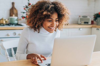 Koyu tenli kız dizüstü bilgisayara bakar ve online alışveriş yapmayı sever.