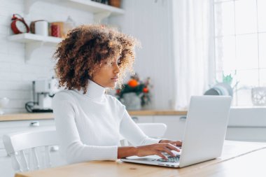 Koyu tenli kız dizüstü bilgisayara bakar ve online alışveriş yapmayı sever.