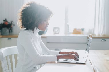 Koyu tenli kız dizüstü bilgisayara bakar ve online alışveriş yapmayı sever.