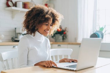 Koyu tenli kız dizüstü bilgisayara bakar ve online alışveriş yapmayı sever.