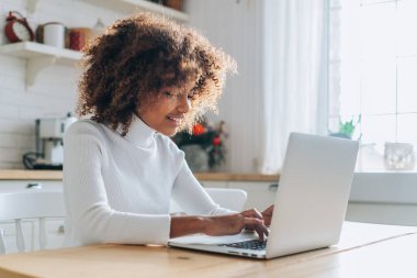 Koyu tenli kız dizüstü bilgisayara bakar ve online alışveriş yapmayı sever.