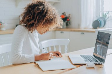 Öğrenci kız gri deftere karşı oturuyor ve notlar yazıyor.