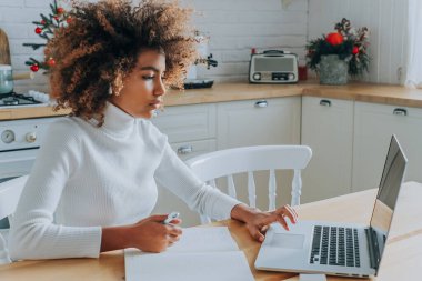 Öğrenci kız gri deftere karşı oturuyor ve notlar yazıyor.