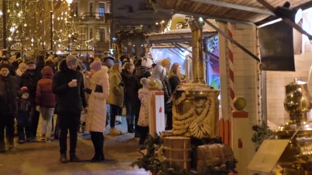 Orvosi védőmaszkos emberek sétálnak a karácsonyi piacon a város központjában egy téli estén. Oroszország, St. PETERSBURG, DECEMBER 26, 2020 — Stock videók