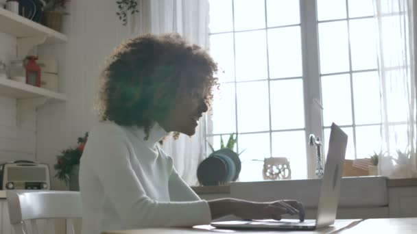 Χαριτωμένη Αφρο-Αμερικανός γυναίκα απολαμβάνει τα καλά νέα, πληκτρολογώντας σε ένα γκρι σημειωματάριο — Αρχείο Βίντεο