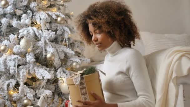 Lady houdt huidige doos tegen ontwerper witte kerstboom — Stockvideo
