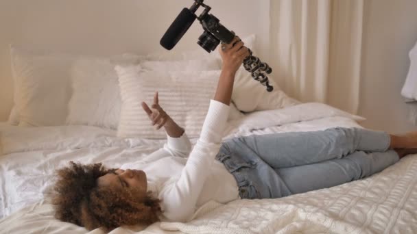 Blogger sostiene la cámara y hace video selfie tumbado en la cama — Vídeos de Stock
