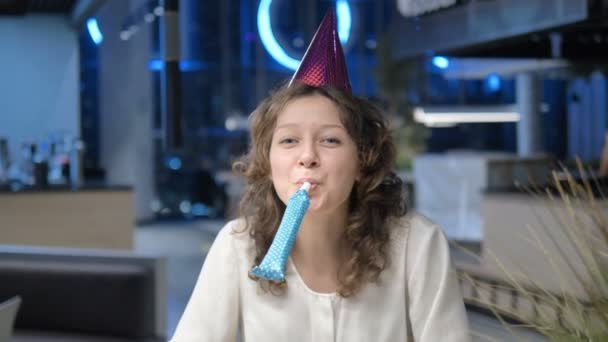 Woman with cone on head blows to camera claps and smiles — Stock Video