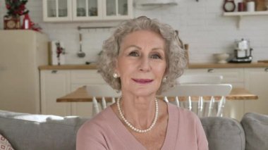 İnci kolye takan hoş, yaşlı kadın nazikçe gülümsüyor.