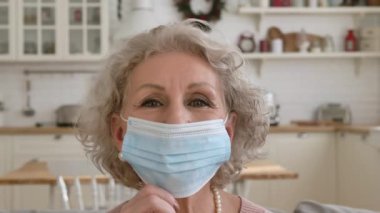 Emekli kadın koruyucu maskeyi indirir ve nazikçe gülümser.