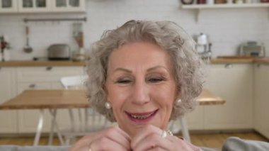 Kısa gri saçlı emekli kalp şeklinde el ele tutuşuyor.