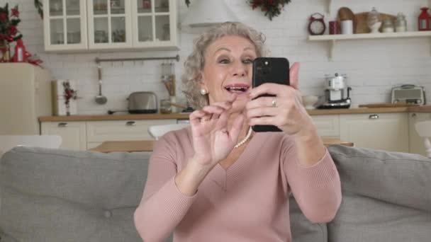Pensioner houdt telefoon in de hand glimlacht en toont cool teken — Stockvideo