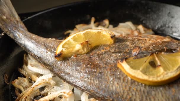 Pfanne mit gebratenem Dorada-Fisch auf Zwiebelscheiben und Zitrone obendrauf — Stockvideo