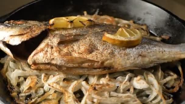 Pan met gebakken dorada vis op ui plakjes en citroen op de top — Stockvideo