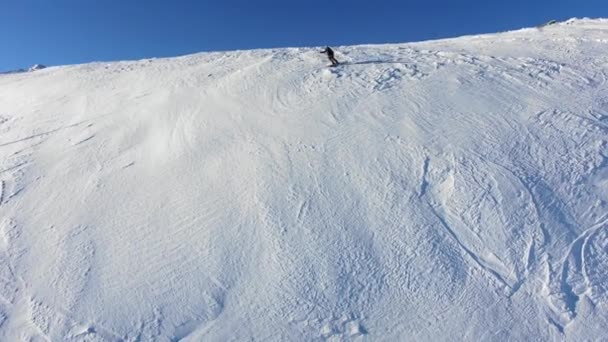 Skieur extrême glisse sur une pente de neige raide dans les montagnes entre les rochers vue aérienne — Video