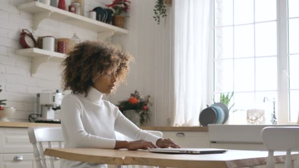 Donkere dame zit aan tafel en opent laptop in de keuken — Stockvideo