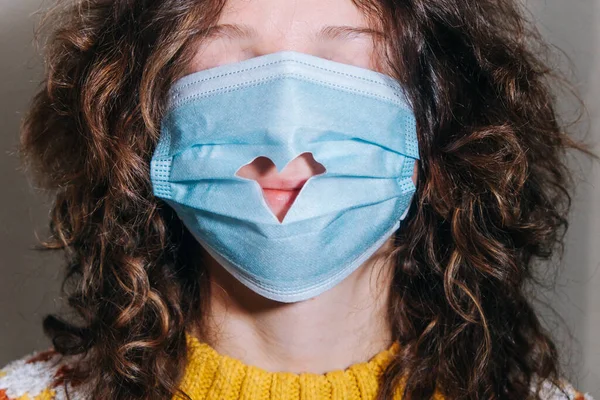 Medische masker op het gezicht van een meisje met een uitgesneden hart close-up en vrouwelijke lippen, Valentijnsdag viering — Stockfoto