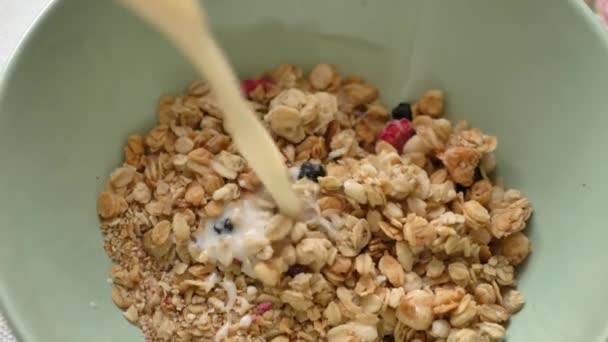 O leite é derramado no prato de cereais de pequeno-almoço, close-up. Alimentação saudável. — Vídeo de Stock