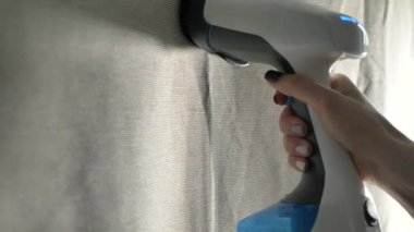 Buruşuk bir kumaşı okşamak için buharlı gemi kullanan bir kadının eli.