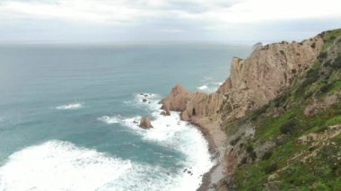 Çift okyanusta uçurumun kenarında duruyor, İHA tepemizde uçuyor.