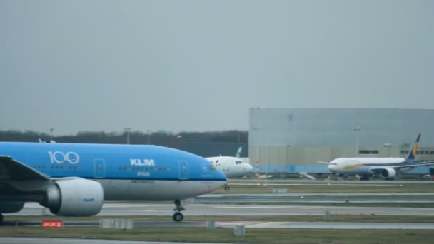 Vliegtuig stijgt op vanaf startbaan tegen terminal op Schiphol — Stockvideo