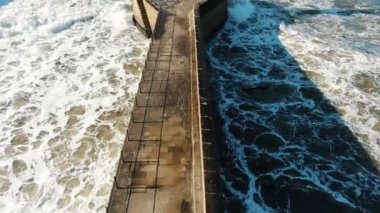 Okyanus deniz feneri tabanını yener, ufka karşı köpük yapar.