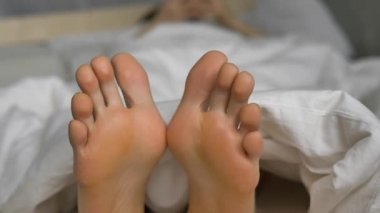 Yumuşak yorganı olan genç ayak parmakları yatakta dinleniyor.