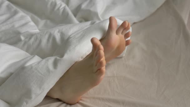 Молодой человек с мягким одеялом извивается пальцы ног покоится в постели — стоковое видео