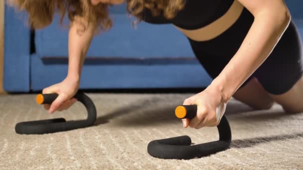 Femme fait push-ups s'appuyant sur des stands spéciaux sur le sol — Video