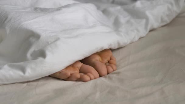 Pessoa sonolenta coberto com cobertor wriggles dedos dos pés na cama — Vídeo de Stock