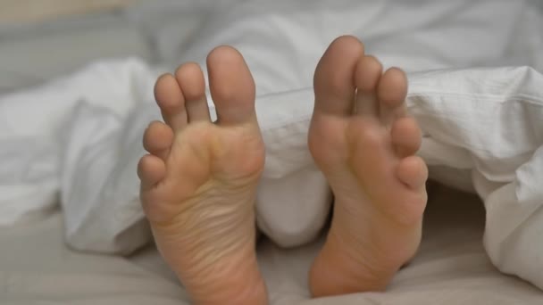 Ung person med bløde dynehåndled tæer hviler i sengen – Stock-video