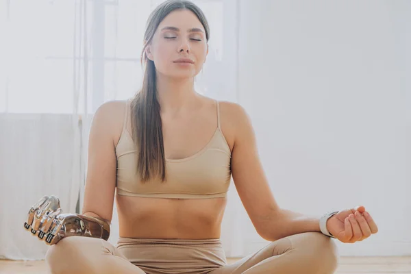 Peaceful woman with prosthesis arm meditates in sunny room