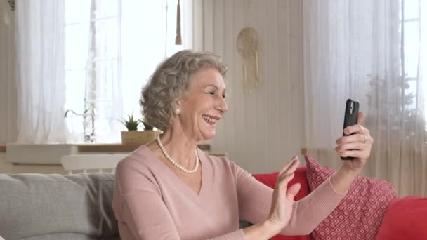 Nice elderly woman conducts video call holding smartphone — Stock Video