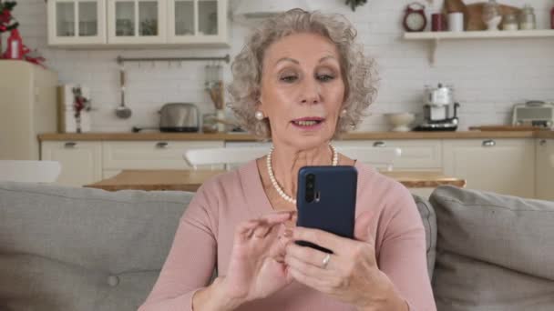 Wanita yang sudah pensiun mengirimkan ciuman udara terhadap kamera depan smartphone — Stok Video