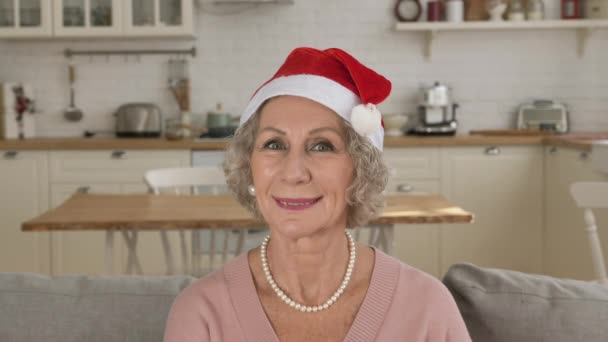 Starší dáma v klobouku Santa Claus na hlavě úsměvy v kuchyni