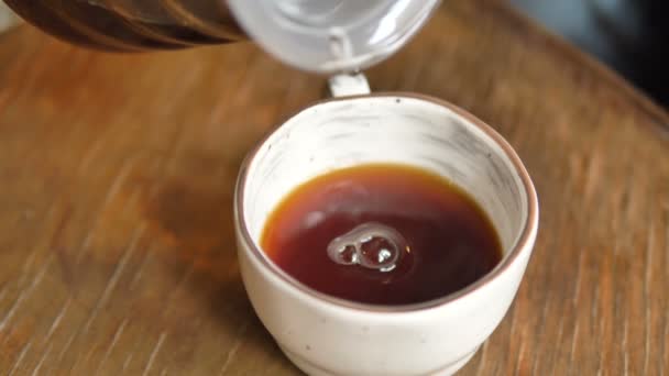 Dark brown filter coffee pouring into white ceramic cup — Stock Video